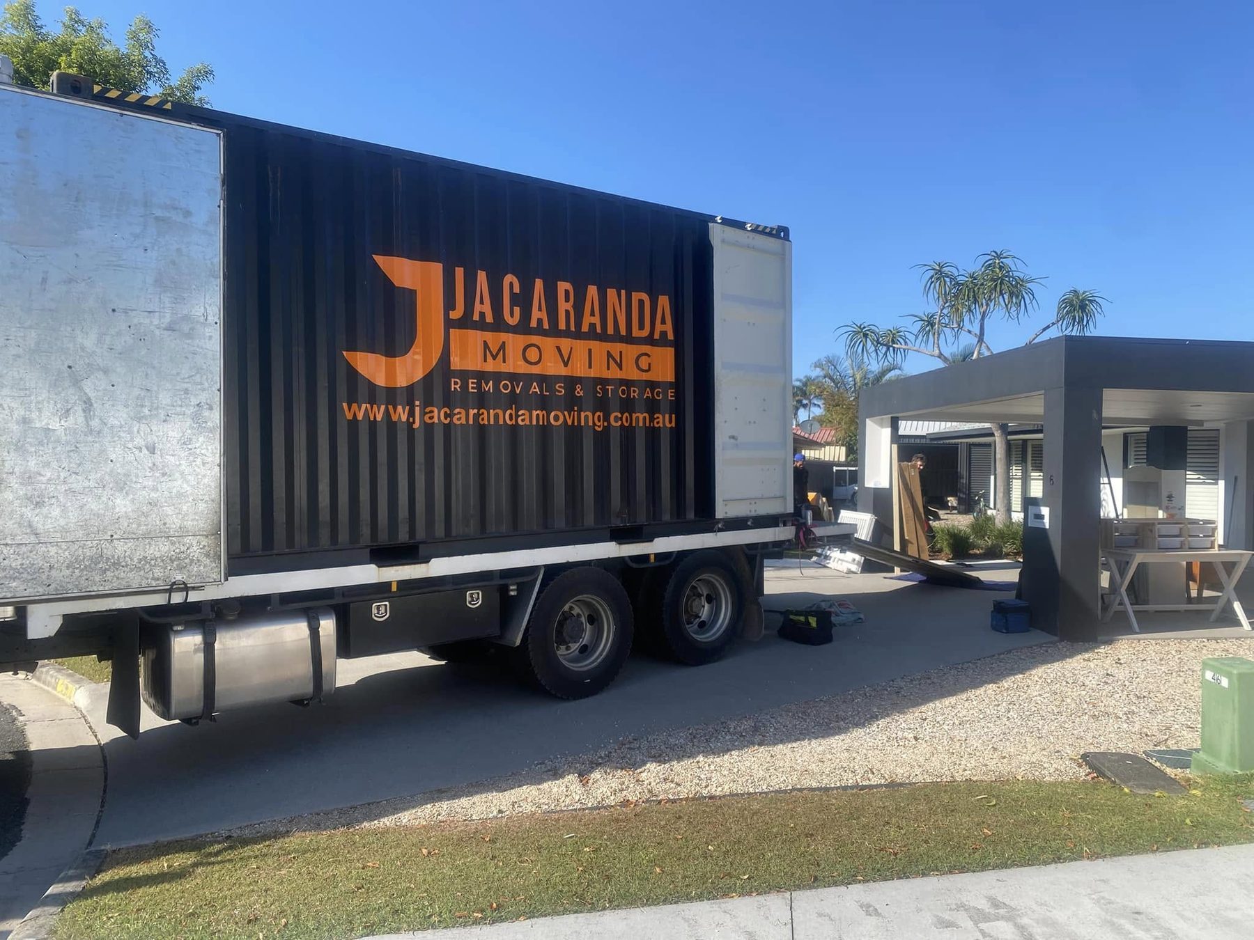 A Jacaranda-branded shipping container being delivered to a Gold Coast home